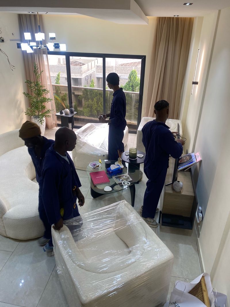 Pack n Moove team wrapping cream furniture in protective film inside an upscale Lagos apartment before moving day