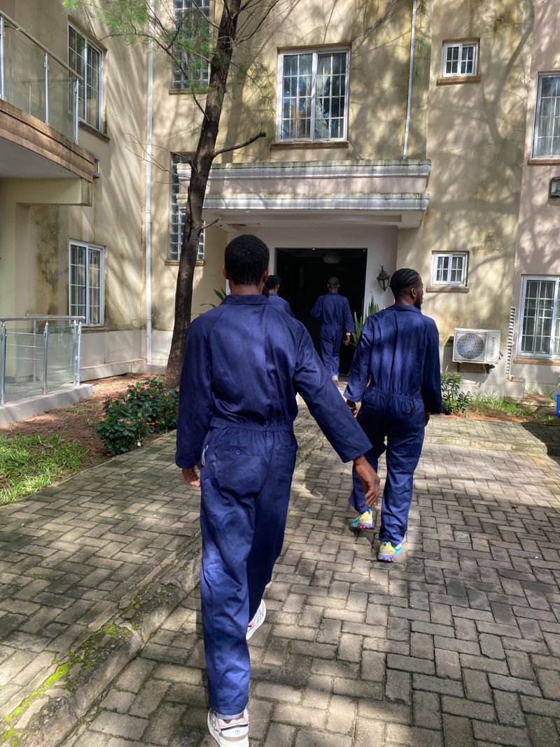 Uniformed Pack n Moove moving crew walking into a Lagos apartment building to start a relocation job